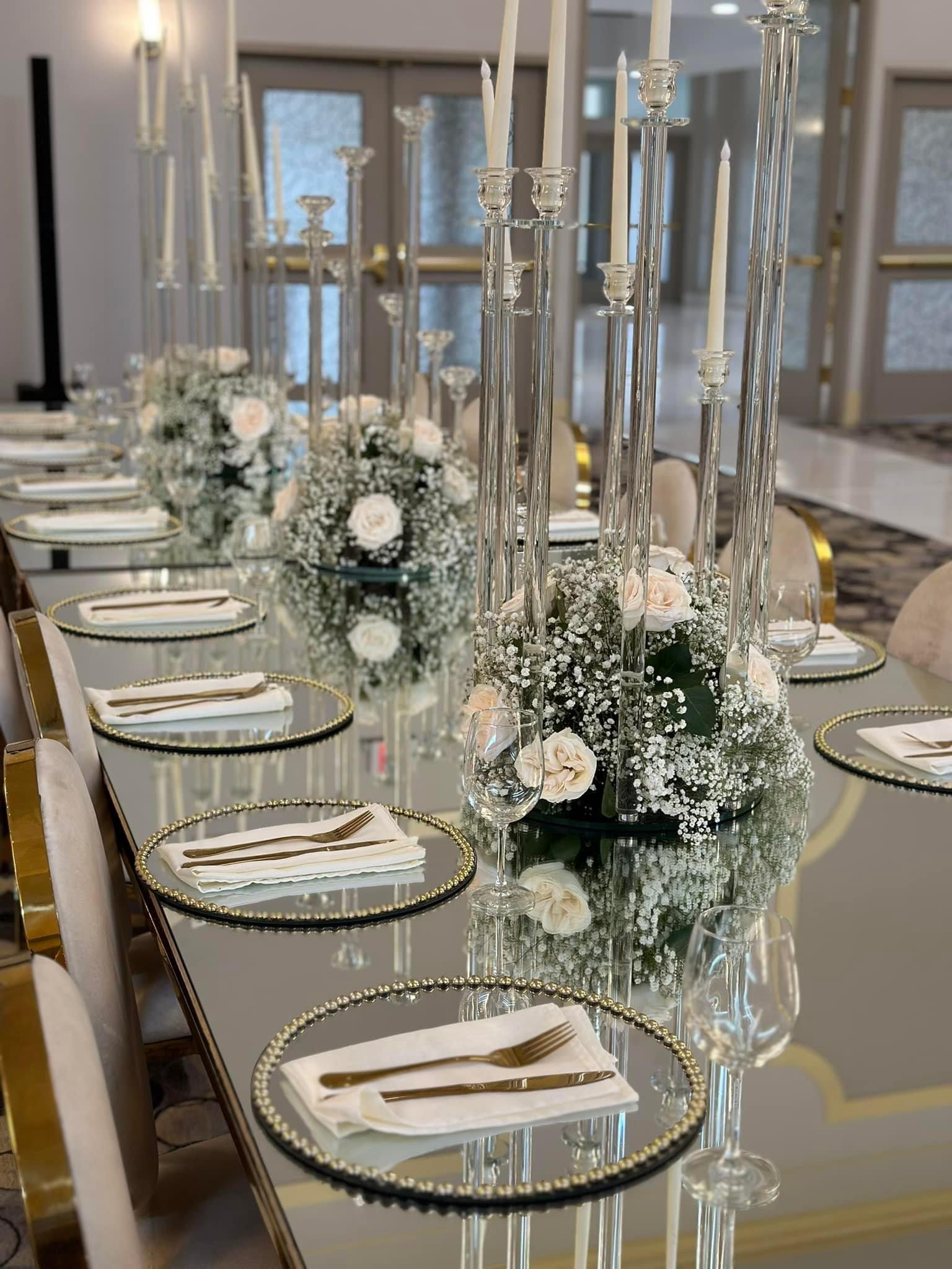 Reception table with fine glassware, floral centerpiece and tall crystal candleholders