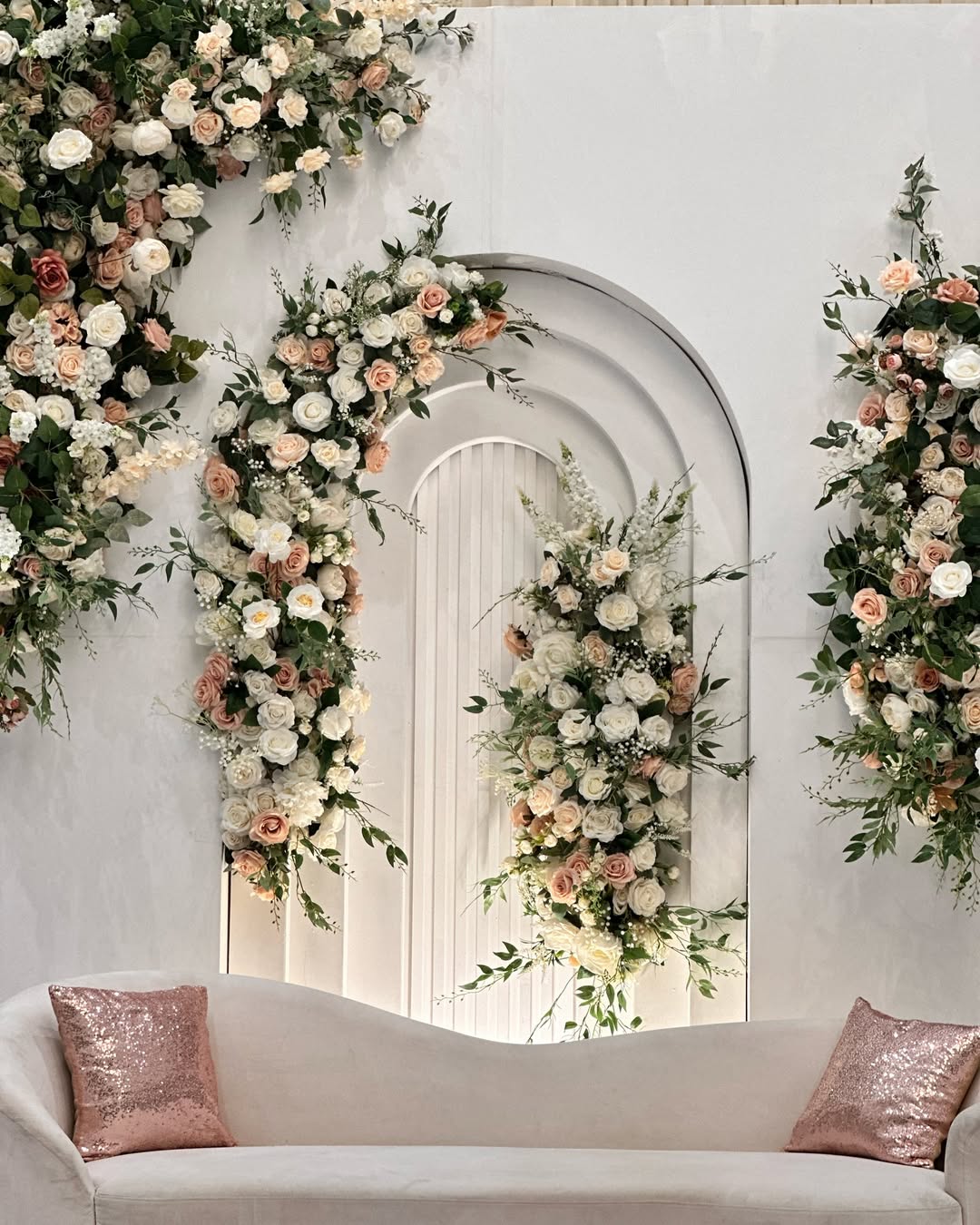 White sweetheart sofa framed by blush and ivory flowers